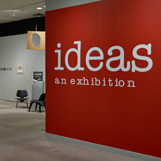 A red wall with the words "ideas an exhibition"