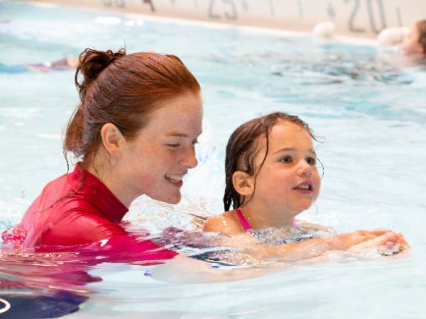 Woman teaching swim lessons to young child. 