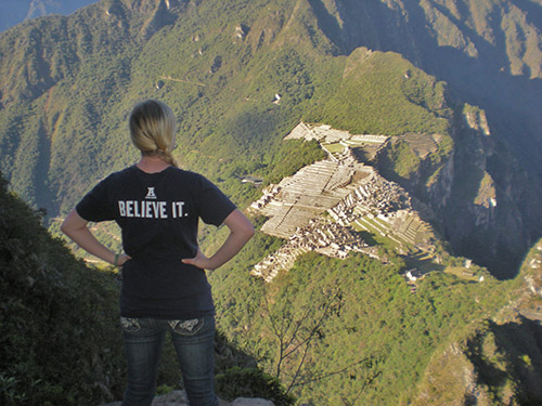 A USU student overlooks ancient ruins from above on a mountain peak