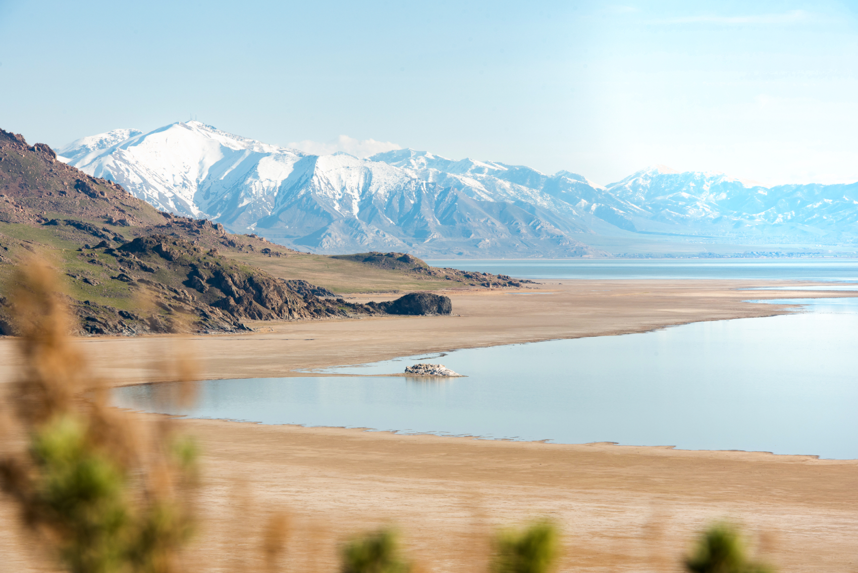 the great salt lake at medium tide, with mountains in the background and a white salty beach showing how far the lake has fallen.