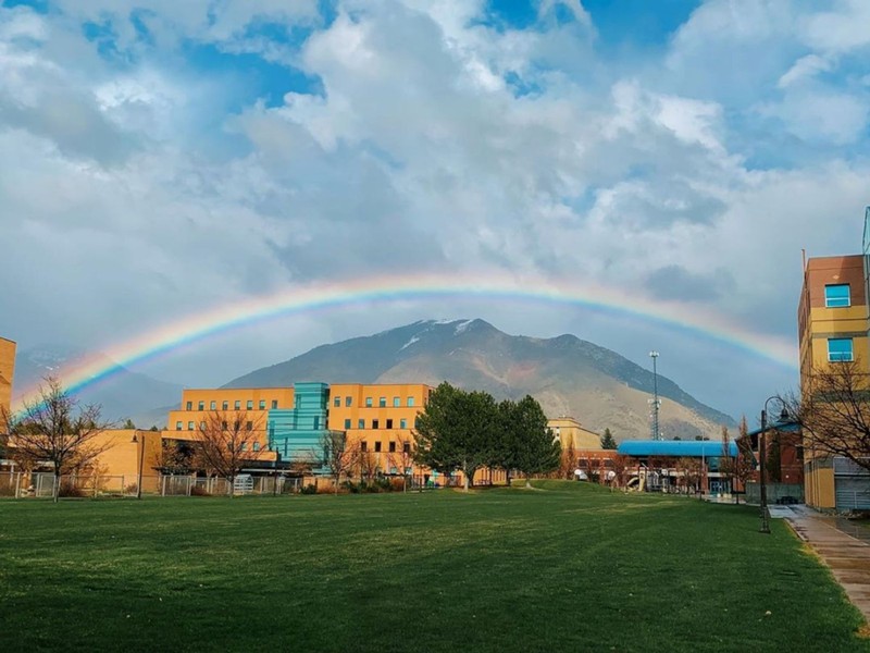A large rainbow arches over the Logan campus