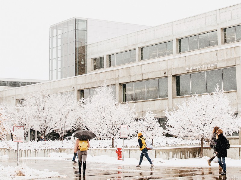 Students walking pass the library in the snow.