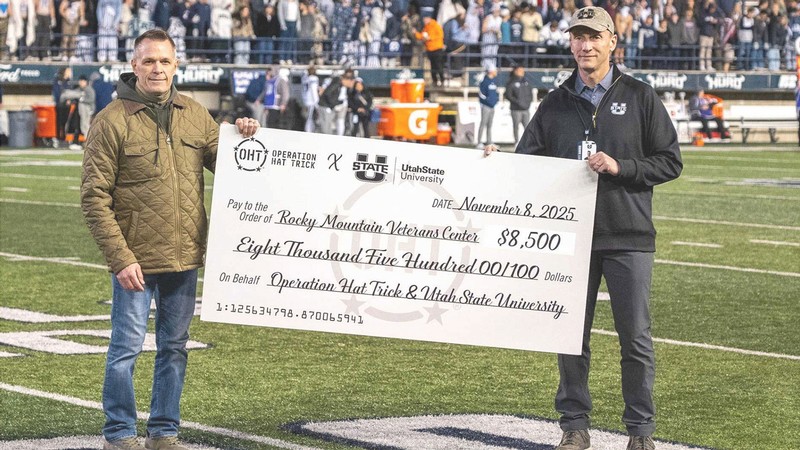 Two people holding a giant check at a football game.