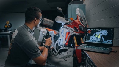 A person scanning a motorcycle with an imaging device.