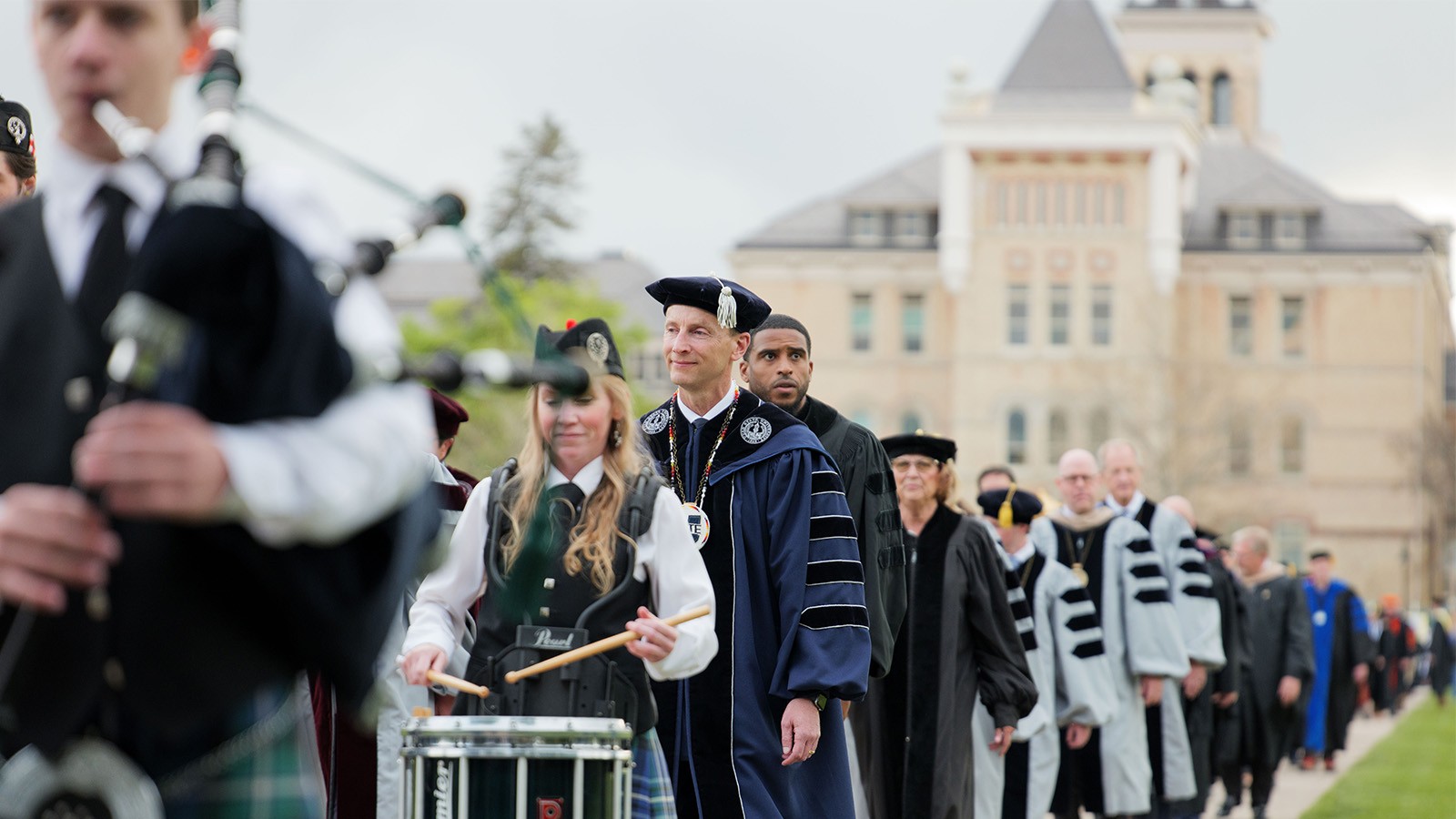 People walk along USU's Quad in cap and gown